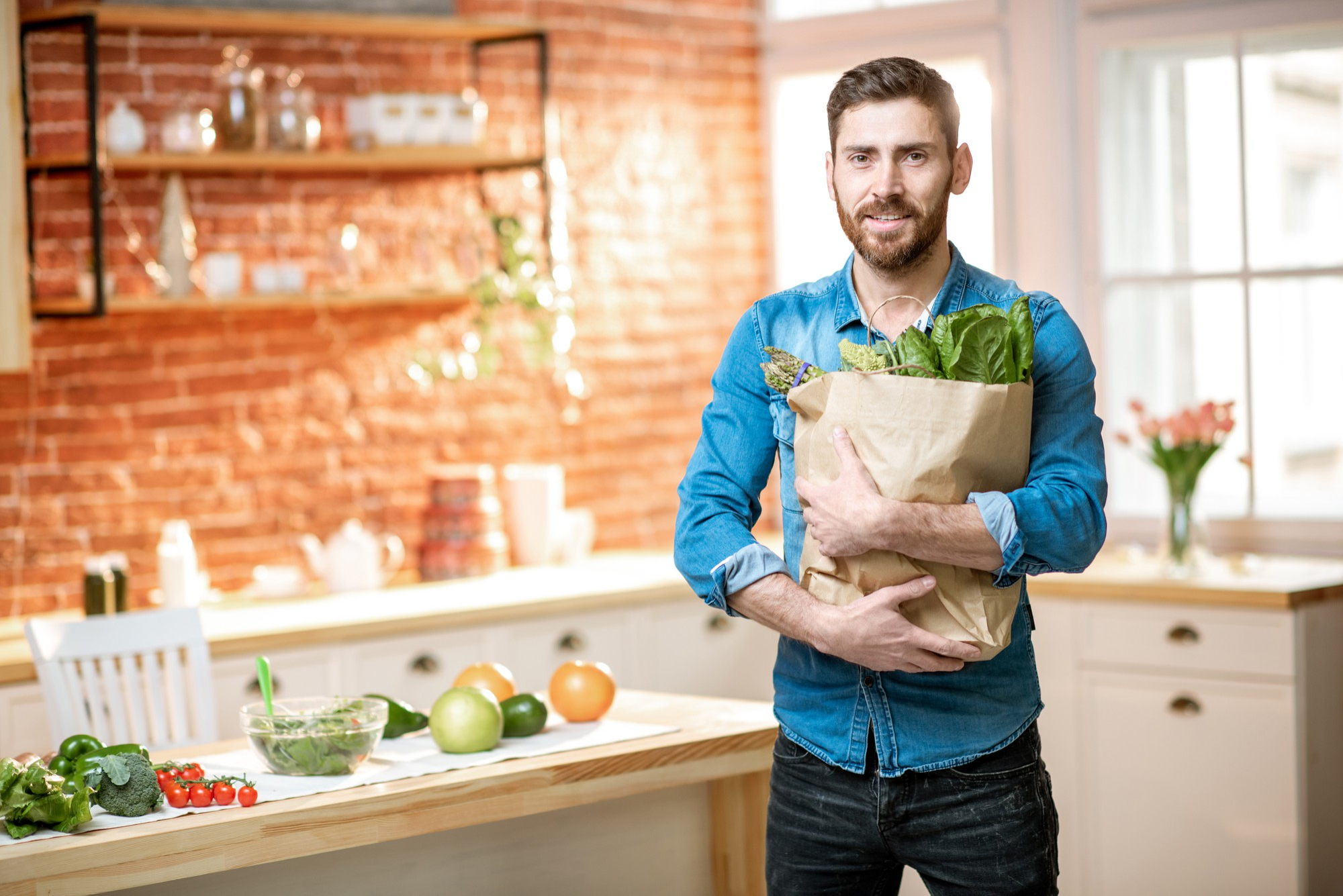 Hombre preparando vegetales y una comida cotidiana en una cocina cálida